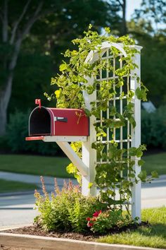 a mailbox is attached to a white trellis with plants growing out of it