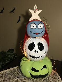 three pumpkins decorated as jack skellingy faces on top of each other