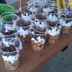 small cups filled with marshmallows and chocolate chips on a table next to a bag of peanuts