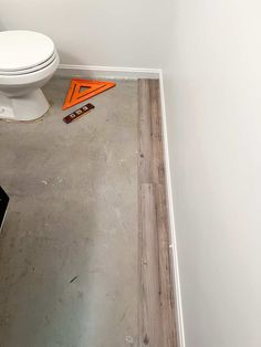 a bathroom with a white toilet sitting on top of a hard wood floor