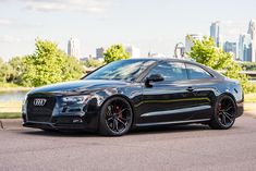 a black car parked in front of a city skyline