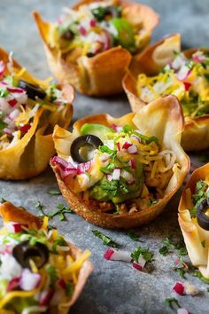 small appetizers filled with various toppings on top of a countertop, ready to be eaten