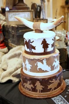 a three tiered cake is decorated with cowboy silhouettes