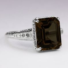 This vintage style ring features an emerald cut smoky quartz set in a sterling silver setting. The Art Deco style setting is beautifully crafted with romantic engraved details. The smoky quartz is a natural, earth mined stone. The ring measures 12mm across (north south) and 6mm from finger to top.Please note that colors can vary slightly depending on your monitor and display settings. The video features this setting with a sky blue topaz center. This version is also available in our shop. Classic Brown Rectangular Jewelry, Classic Jewelry With Accent Stones For Collectors, Classic Silver Octagon Emerald Ring, Classic Silver Emerald Ring With Rectangular Stone, Classic Smoky Quartz Jewelry As Gift, Classic Smoky Quartz Rings For Formal Occasions, Vintage Emerald Cut Jewelry With Bezel Setting, Classic Smoky Quartz Jewelry As A Gift, Elegant Smoky Quartz Gemstone Rings