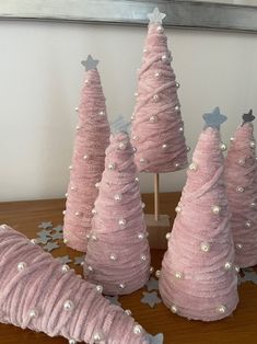 three pink christmas trees with silver stars on them and one is made out of yarn