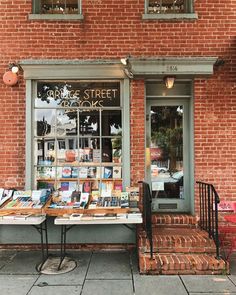 an outside book store with books on the tables and in front of it is a red brick building