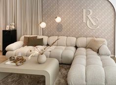 a living room filled with furniture and a monogrammed wall behind the sectional sofa