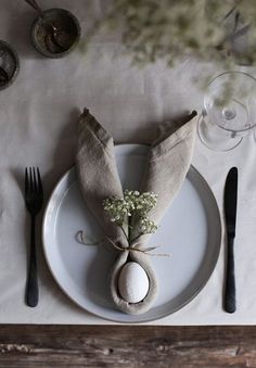 a place setting with napkins, silverware and an egg on a white plate