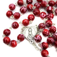 Features: Ruby Red color with swirl effect on beads Heart medallion with Fatima imagery on both sides Rosary measures 23" Diameter of the beads: 7 mm Made in Fatima, Portugal Product Description: Celebrate our Lady of Fatima with this beautiful ruby red glass rosary. Hand made in Fatima, Portugal, this rosary is a great way to commemorate Our Lady of Fatima. A classic handmade rosary and Fatima medallion to commemorate Mary's apparitions in Portugal. Red Round Beads Necklace For Valentine's Day, Red Round Beaded Necklaces For Valentine's Day, Adjustable Red Rosary With 8mm Beads, Red 8mm Beaded Jewelry For Valentine's Day, Red Heart Beads For Jewelry Making, Red Heart Beads For Gifts, Red Rosary Beads For Jewelry Making, Red Beaded Rosary For Spiritual Use, Adjustable Red Rosary With Round Beads