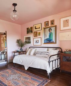 a living room with pink walls and pictures on the wall, including a white couch