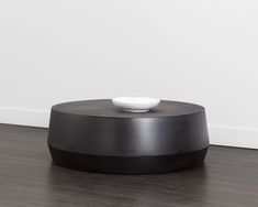 a white bowl sitting on top of a black coffee table in front of a white wall