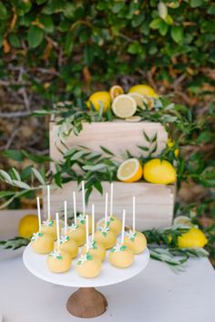 lemon cake pops on a white plate with green sprinkles and lemons in the background