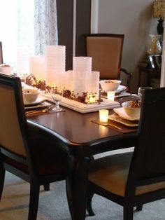 a dining room table is set with candles and plates on the placemats in front of it