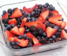 berries and blueberries in a glass dish on a white counter top, ready to be eaten