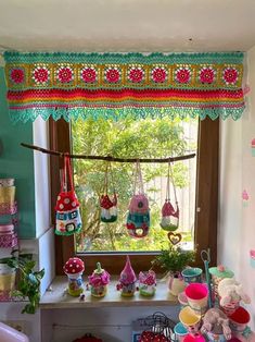 a kitchen window covered in lots of colorful items and decorations, including teapots