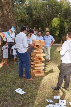 several men are playing with wooden blocks in the grass