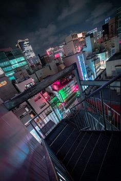 the city is lit up at night with bright lights on it's buildings and stairs