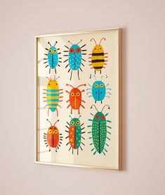 an insect print hangs on the wall in front of a pink wall with a white frame