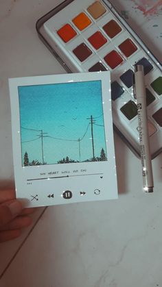 a person holding up a card with an image of power lines on it next to some watercolors