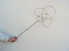 a hand holding a string attached to a kite on the side of a white wall