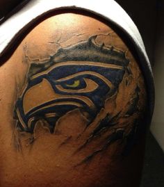 the back of a man's shoulder with an eagle and eye tattoo on it