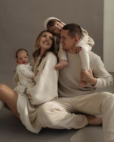 a man, woman and baby are sitting on the floor with their arms around each other