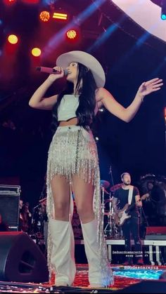 a woman in white outfit and cowboy hat on stage