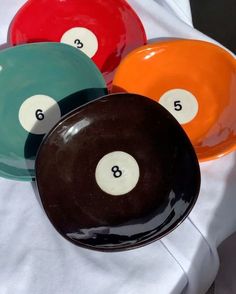 three different colored pool balls sitting on top of a white cloth covered table with numbers