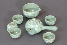 a green tea set with cups and saucers