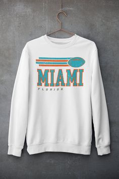 Dolphins Sweatshirt - Vintage Dolphins Sweatshirt - Miami Sweatshirt - Fins Up Sweatshirt - Florida Sweatshirt - Dolphins Football Gift  -- UNISEX -- 💎PRODUCT DETAILS & SIZING ** Gildan 18000, unisex heavy blend crewneck sweatshirt ** Pre-Shrunk 50% Cotton/50% Polyester made with softer air-jet spun yarn ** Size chart can be found on listing photos ** Unisex fit, runs true to size ** Colors may be slighty brighter in the mockups 👕CARE INSTRUCTIONS ** Machine wash cold, inside out, with like colors ** Only non-chlorine bleach ** Tumble dry low/but hang dry works best ** Medium Iron ** Do not iron graphic ** Do not dry clean ⏱️SHIPPING AND PRODUCTION TIME ** Production time is 1-5 business days ** Shipping time is 2-5 business days 👐FEEDBACK ** I would highly appreciate your feedback as a Fan Apparel Long Sleeve Top With Logo Print, Long Sleeve Logo Print Fan Apparel Top, Long Sleeve Fan Apparel Top With Logo Print, Crew Neck Top With Screen Print Fan Apparel, White Long Sleeve Tops For Fan Gear, White Team Spirit T-shirt For Fall, Screen Print Crew Top For Sports Events, Screen Print Crew Neck Top For Sports Events, Crew Neck Top With Screen Print For Sports Events