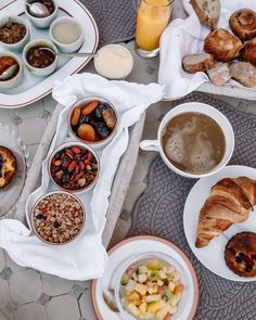 an assortment of breakfast foods are laid out on a table with coffee, croissants and juice