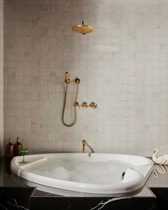 a white bath tub sitting in a bathroom next to a shower head and faucet