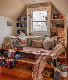 a window seat in the corner of a room with lots of books and pillows on it