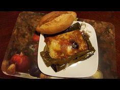 a white plate topped with food on top of a wooden table next to a baguette