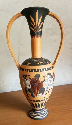 an old vase with some designs on it sitting on a table next to a wall