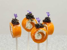 three oranges with blackberries on them are sitting on top of toothpicks