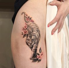 a woman's thigh with a tiger tattoo on it and flowers around the thighs