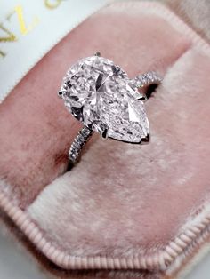 a diamond ring sitting on top of a pink velvet case