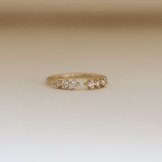 a gold ring with three small diamonds on it's side, sitting on a white surface