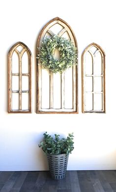 two windows and a potted plant are on the wall in front of each other