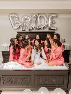 a group of women in pink dresses sitting on top of a bed