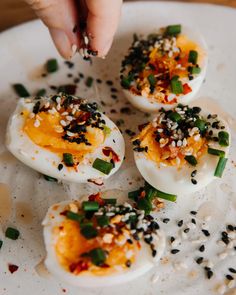 someone is picking up some kind of deviled eggs with black sesame seeds on them