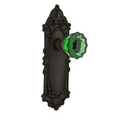 an ornate door handle with a green glass knob on the front and back of it