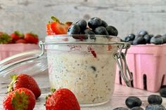 a jar filled with oatmeal and strawberries next to blueberries