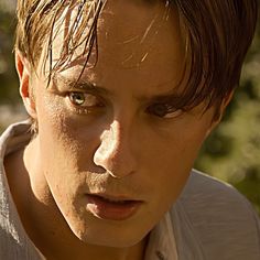 a close up of a person with freckles on his face looking at the camera