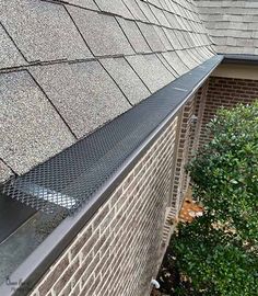 a gutter vent on the side of a brick building next to a green bush