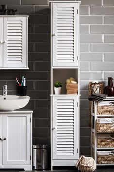 a white sink sitting under a bathroom mirror next to a shelf filled with towels and other items