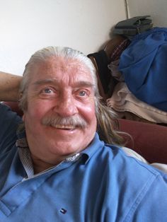 an older man with long hair and a moustache on his face is smiling for the camera