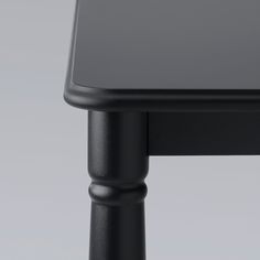 a close up of a black table on a gray background with no one around it