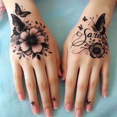 two hands that have tattoos on them with flowers and butterflies painted on the palm of each hand